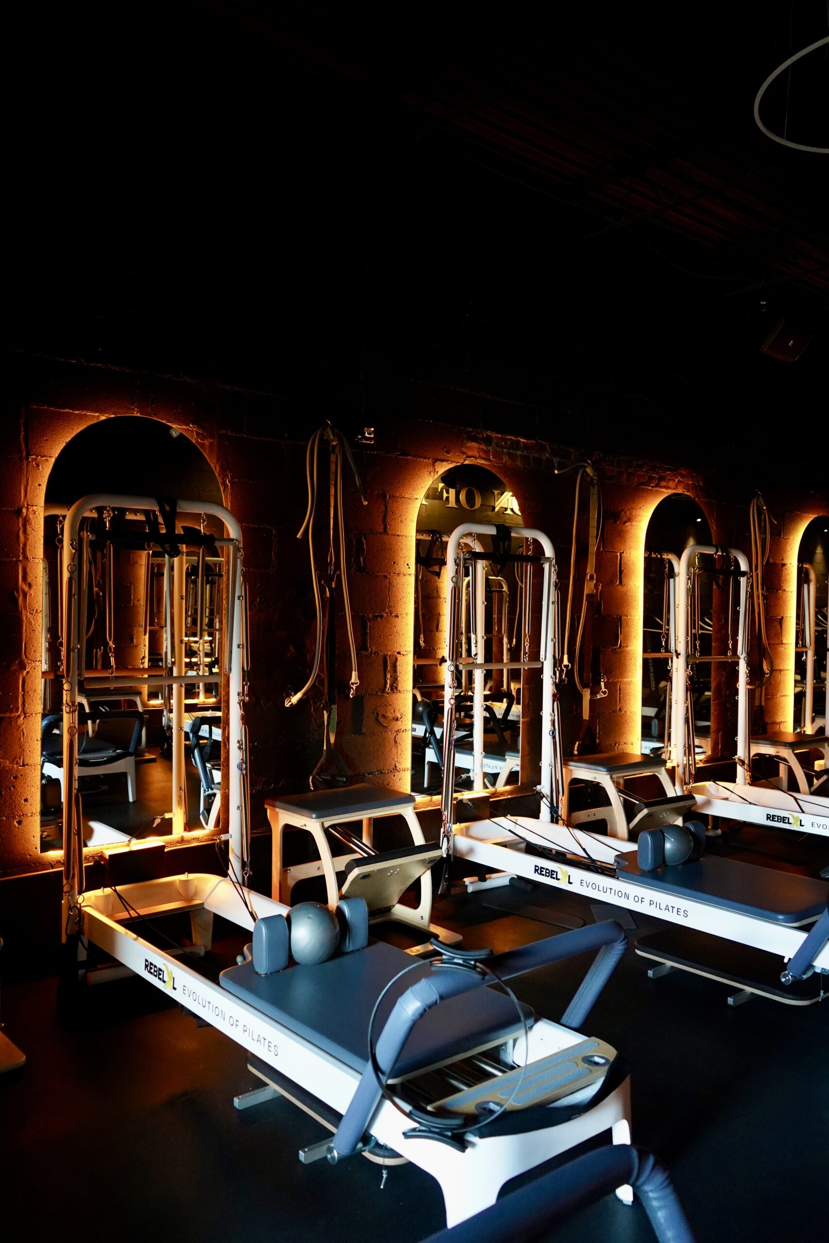 Reformer Pilates machines under arched amber lighting at REBELXL studio, Bergen County NJ